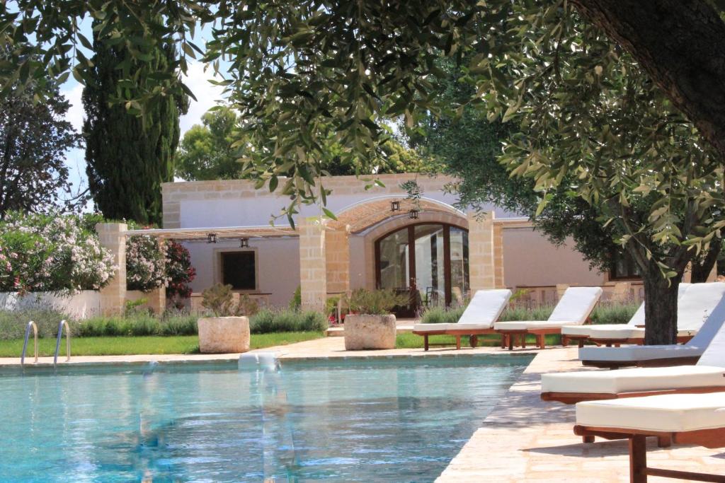 a swimming pool with lounge chairs and a house at Masseria Zambardo in San Vito dei Normanni