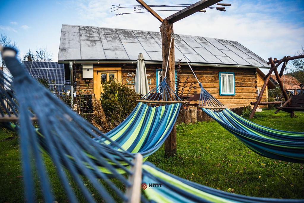 a couple of blue hammocks in front of a log cabin at Myczkowianka Sadyba in Uherce Mineralne