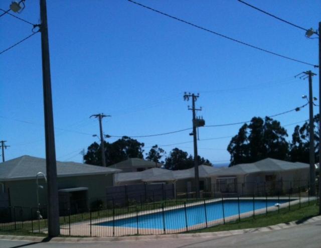 a fence with a swimming pool in front of a building at Casa El Quisco Las Mandarinas in El Quisco