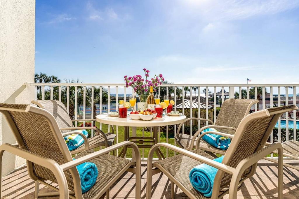 a patio with chairs and a table on a balcony at Islander 203 - Dances with Dolphins in Destin