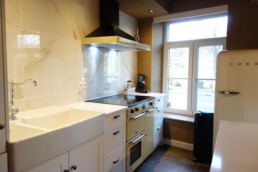 a white kitchen with a sink and a stove at Gîte Citadin "Le Randon" in Spa