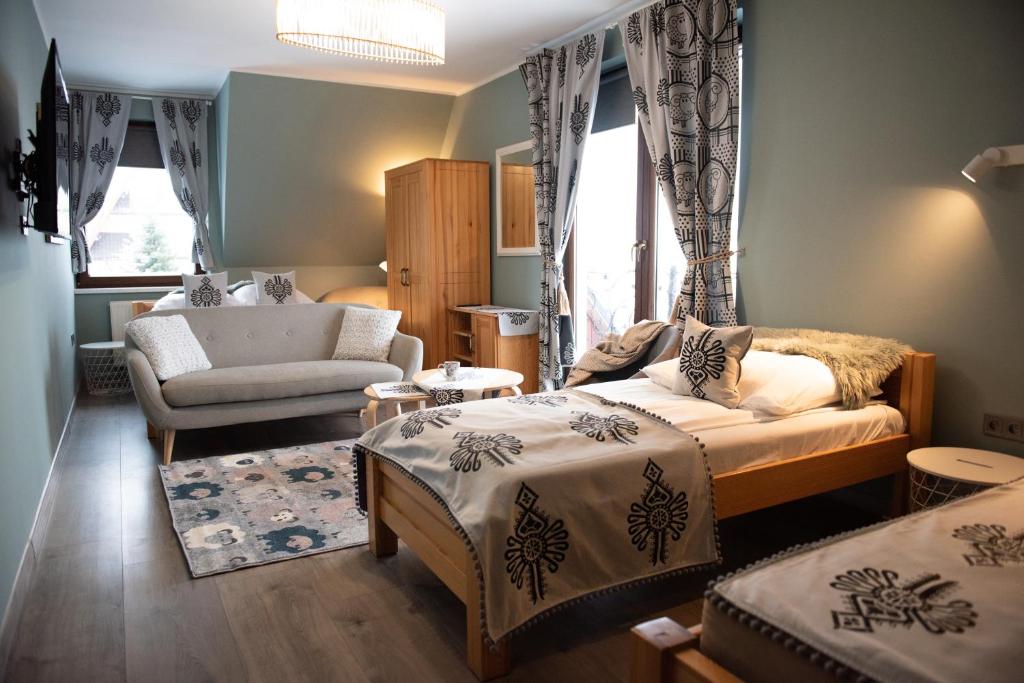 a bedroom with two beds and a chair and a couch at Folkowy Dworek SPA & Fun in Murzasichle