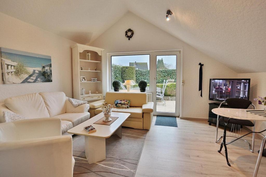 a living room with white furniture and a tv at Hainholz Hainholz Bungalow Hemmelsdorf in Hemmelsdorf