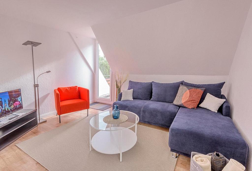 sala de estar con sofá azul y silla roja en Haus Lubecca Ferienhaus Lubecca Appartement 01, en Timmendorfer Strand