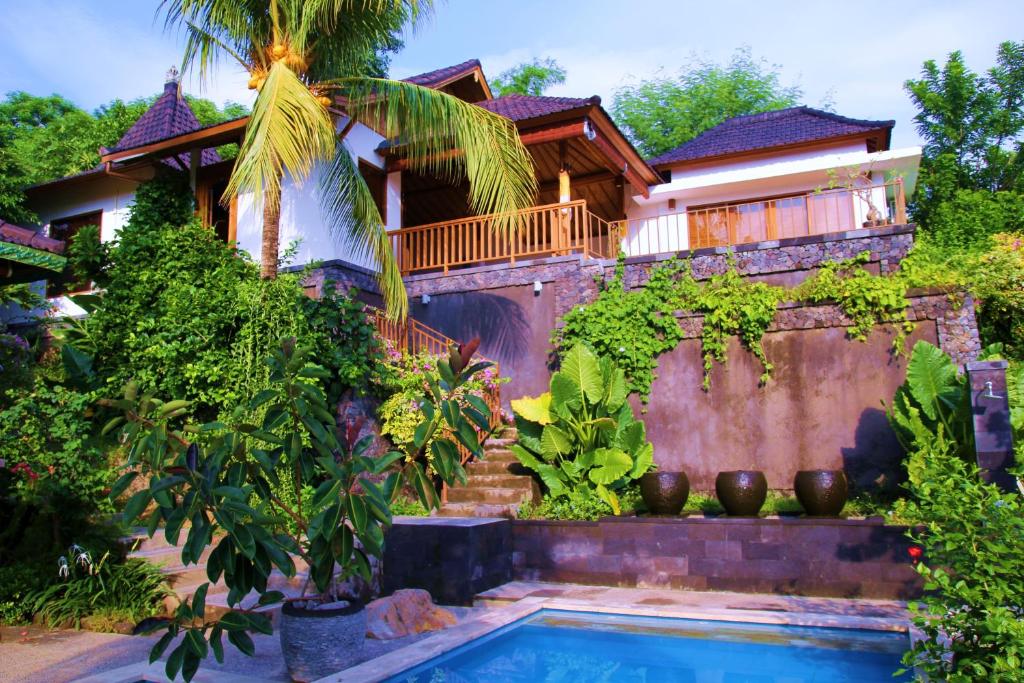 a house with a swimming pool in front of a house at Bali Marina Villa's in Amed