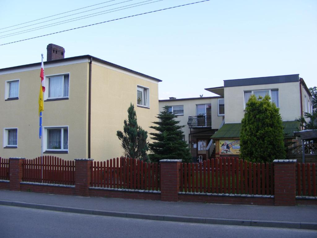 a fence in front of a house with a flag at Pokoje Gościnne Stołówka- Swarzewianka in Swarzewo