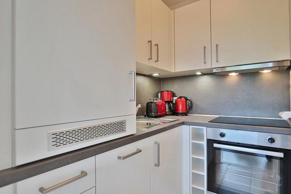 eine Küche mit weißen Schränken und roten Geräten in der Unterkunft Carpe Diem Carpe Diem Appartement 161 in Niendorf