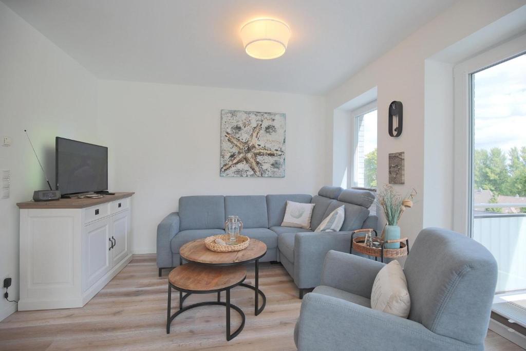 a living room with a blue couch and a tv at Haus Ostseedüne Haus Ostseedüne Appartement 7 in Scharbeutz