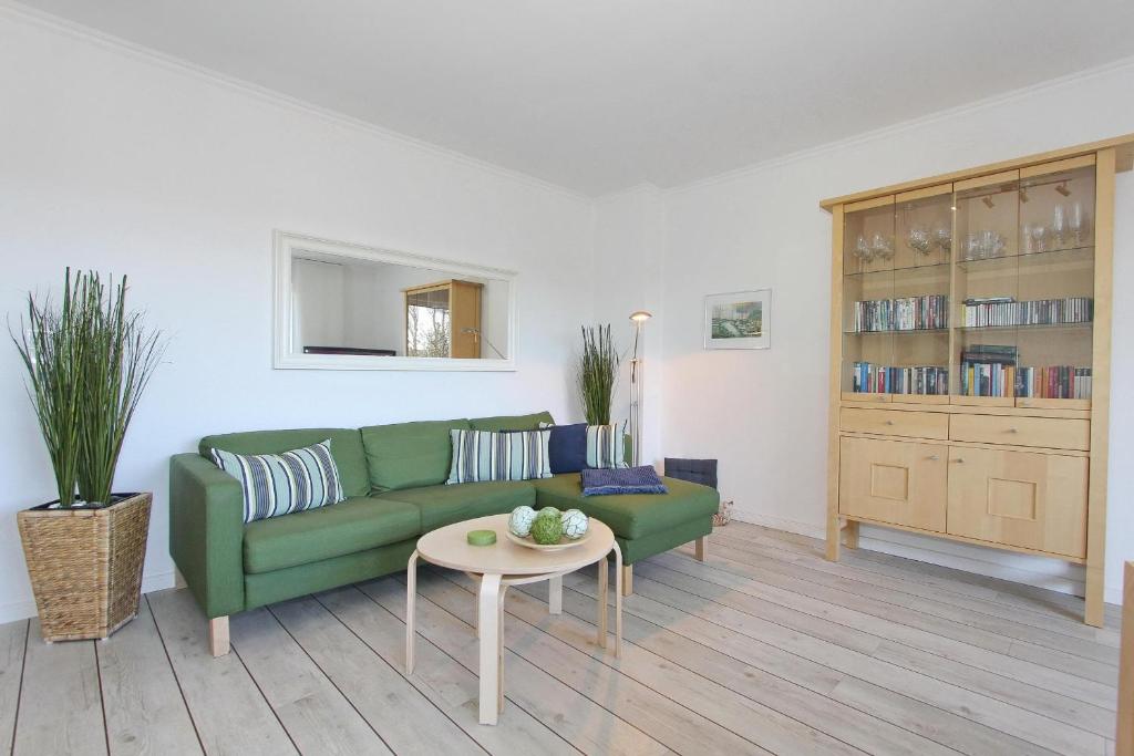 a living room with a green couch and a table at Haus an der Strandallee 112 Haus an der Strandallee 112 Appartement 7 in Scharbeutz