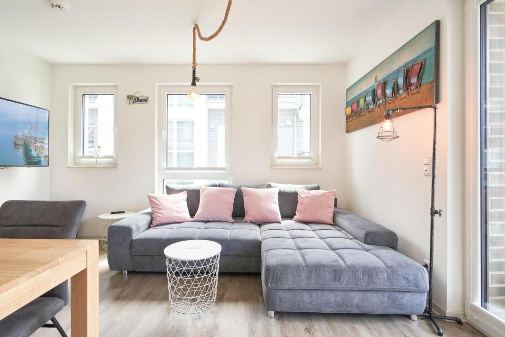 sala de estar con sofá gris y almohadas rosas en Bude 37 Bude 37 Appartement 8 SaM, en Scharbeutz