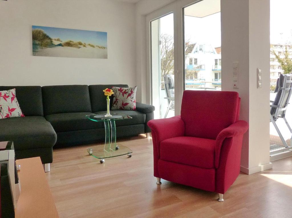 een woonkamer met een bank en een rode stoel bij Strandglück Haus C Strandglück Appartement 15C in Scharbeutz