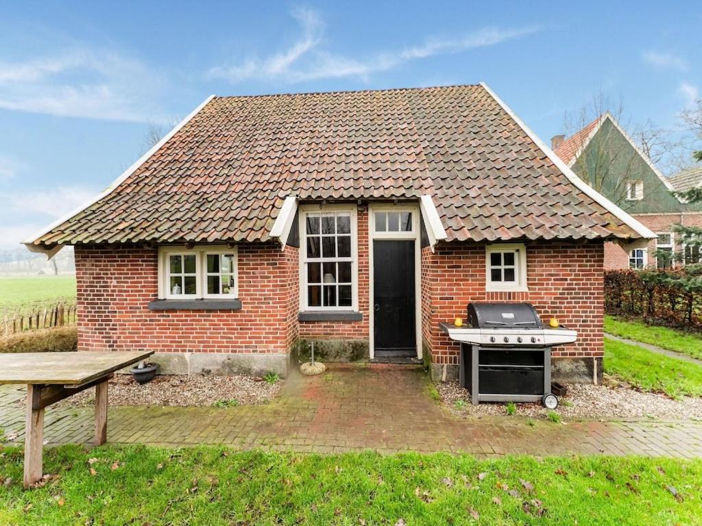 uma pequena casa de tijolos com um grelhador no quintal em House in former bakspieker in rural location near Enschede em Enschede