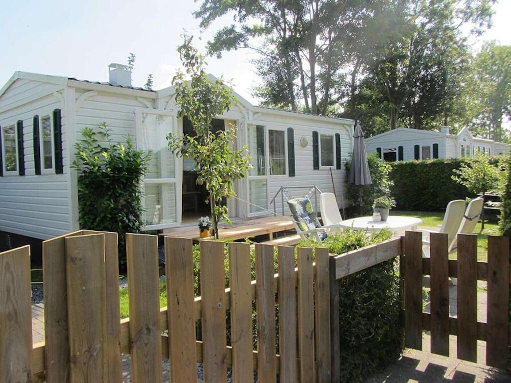 a white house with a fence in front of it at Captivating chalet with a microwave, near the Wadden Sea in Tzummarum