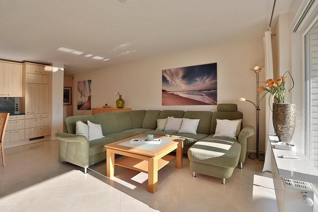 - un salon avec un canapé vert et une table dans l'établissement Wohldkamp 4 Wohldkamp 4 Appartement 04, à Timmendorfer Strand