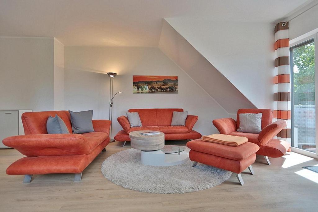 ein Wohnzimmer mit orangefarbenen Stühlen und einem Tisch in der Unterkunft Haus Bergstrasse 4 Haus Bergstraße 4 Appartement 9 in Timmendorfer Strand