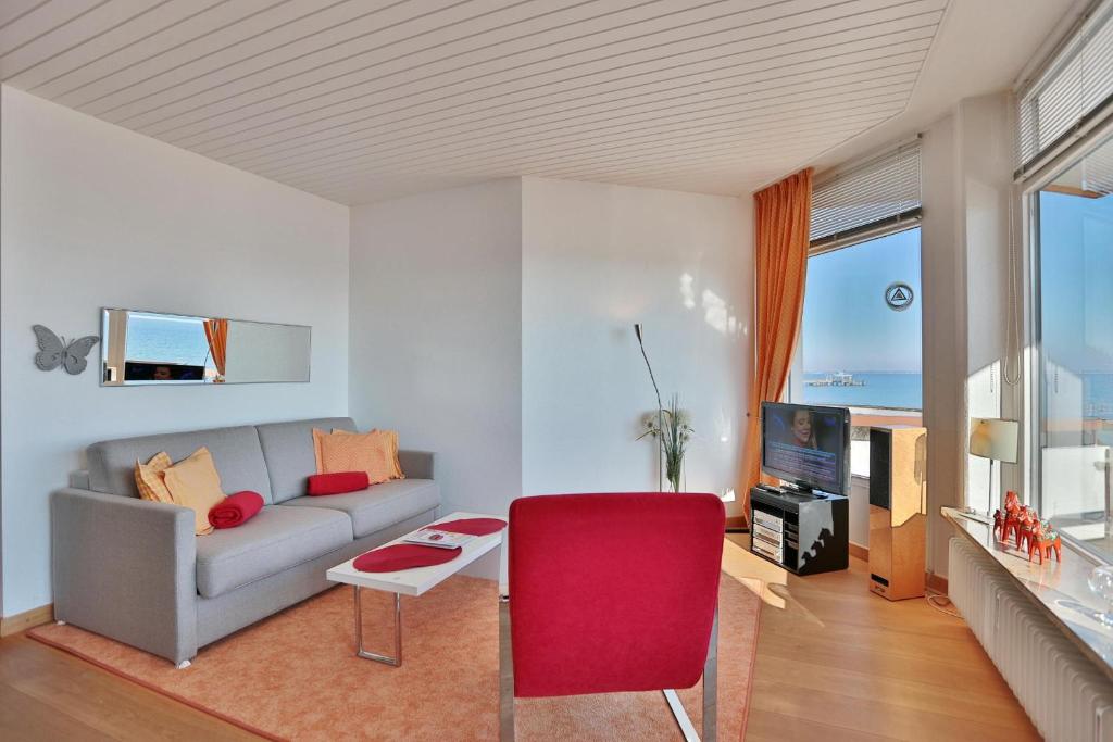 ein Wohnzimmer mit einem Sofa und einem roten Stuhl in der Unterkunft Berliner Hof Berliner Hof Appartement 215 in Scharbeutz