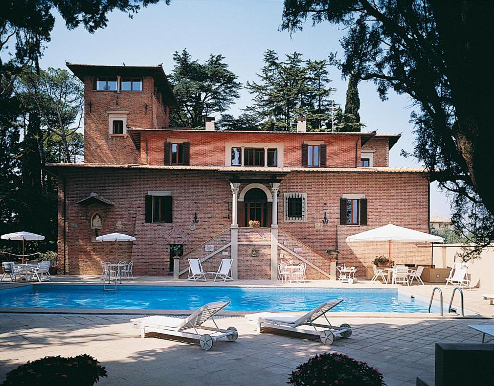 モンテファルコにあるヴィラ パンブッフェッティの大きなレンガ造りの家で、正面にプールがあります。