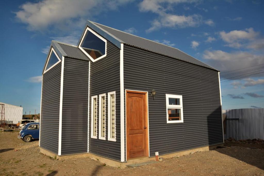 un pequeño edificio negro con puerta y ventanas en Cabañas Pidén en Punta Arenas