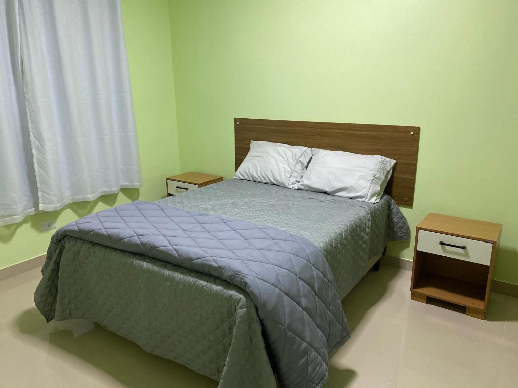 a bedroom with a bed and two night stands at Suítes Acolhedoras da Diva in Alto Paraíso de Goiás