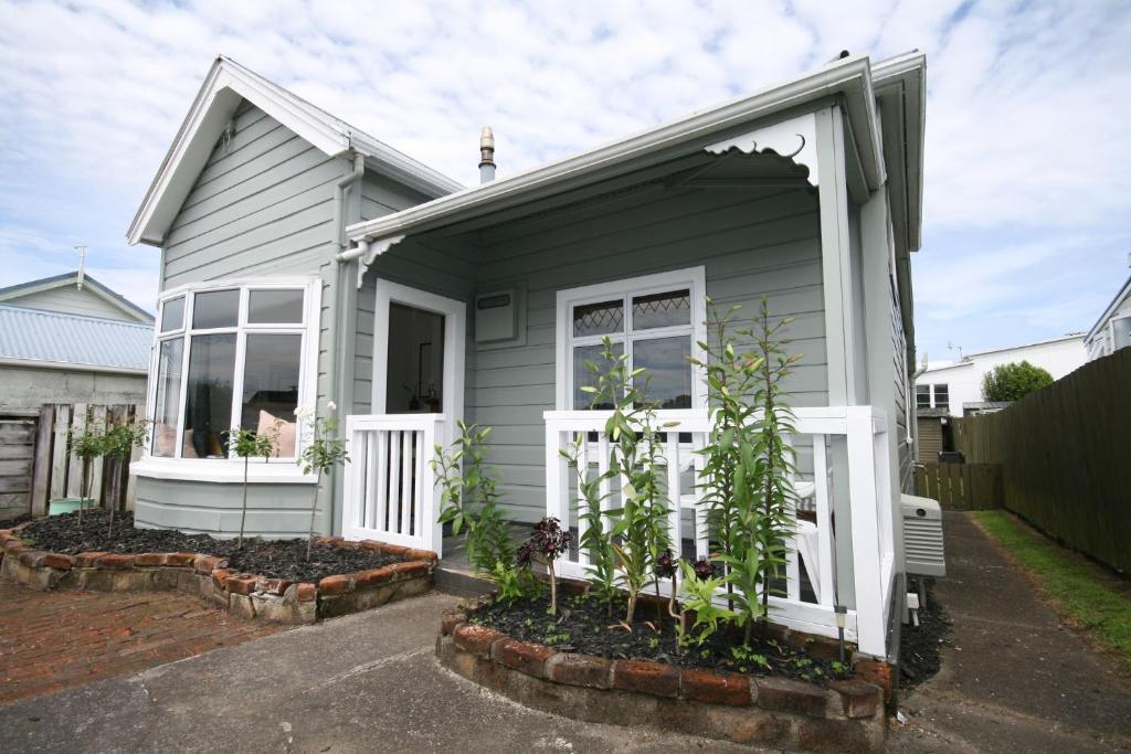 uma casa cinzenta com uma porta branca e algumas plantas em Kingwell Cottage - New Plymouth Holiday Home em New Plymouth