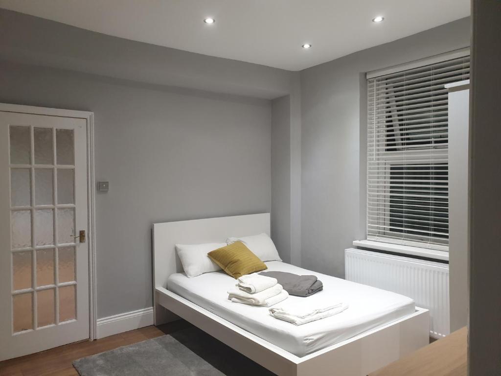 Un dormitorio blanco con una cama con toallas. en Lovely 1 bedroom flat High Barnet 3 mins away, en Barnet