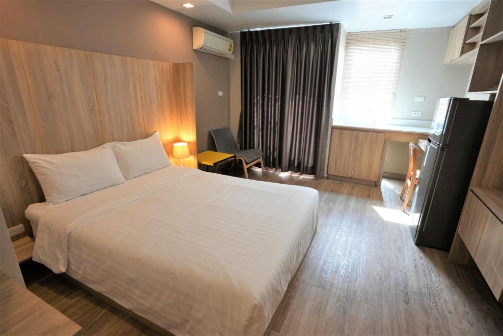 A bright bedroom with a large bed, curtained window and small sitting area.