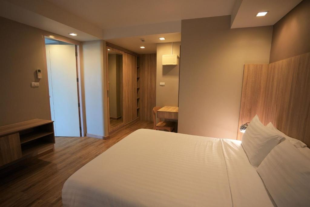 A modern double bedroom with a large bed, built-in storage, and a small wooden table.