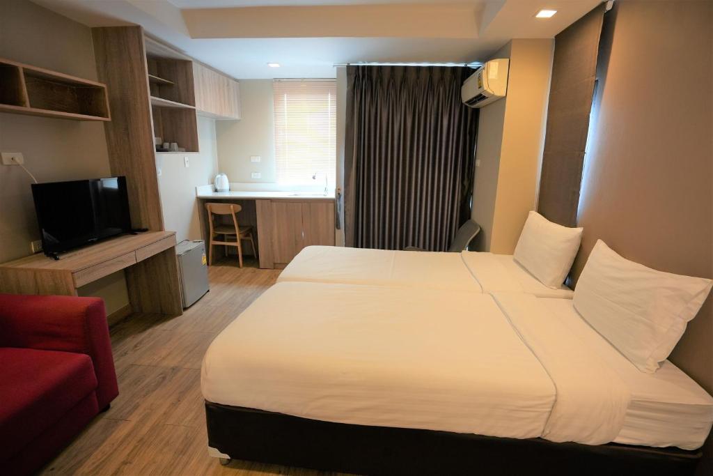 A double bedroom with a red armchair, television, shelving and a window-side work counter.