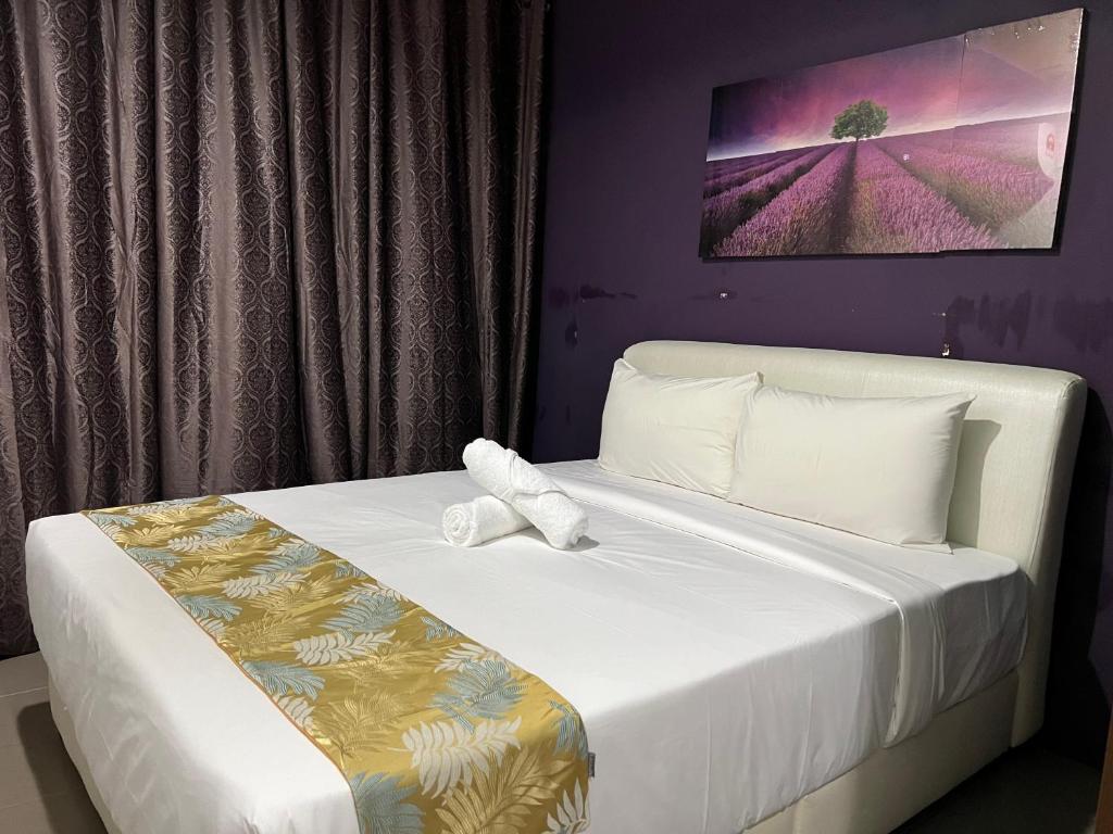 Un dormitorio con una cama blanca con paredes moradas en Cassia Inn Kuching en Kuching
