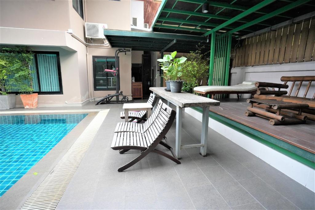 A tiled poolside patio with loungers, a table, and covered seating.