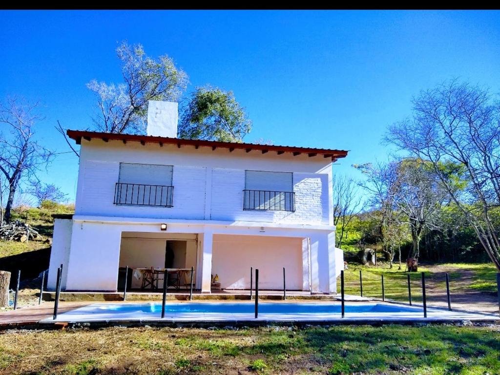 a white house with a porch and a yard at Casa Blanca in Villa Rumipal