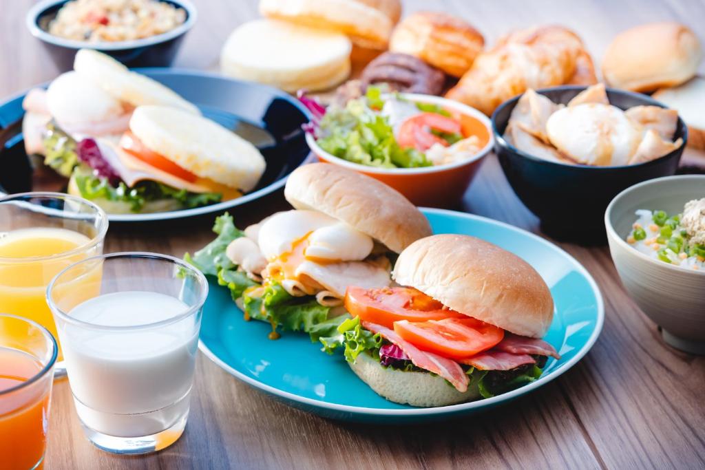 einen Tisch mit Sandwiches und Gläsern Wasser in der Unterkunft JRクレメントイン今治 in Imabari