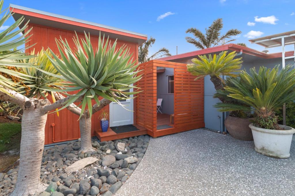 ein Holzhaus mit Palmen davor in der Unterkunft Bach on Wilson - Waihi Beach Holiday Home in Waihi Beach