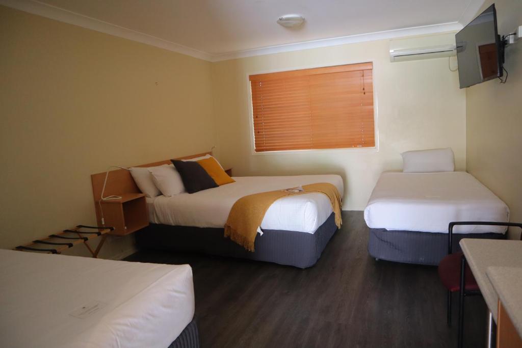 Habitación de hotel con 2 camas y ventana en Country Roads Motor Inn Gayndah, en Gayndah