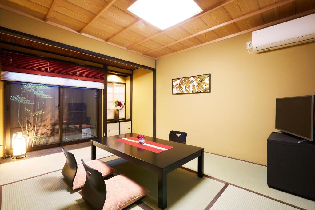 uma sala de estar com uma mesa e cadeiras e uma televisão em Rinn Kujoharikoji 59 em Quioto