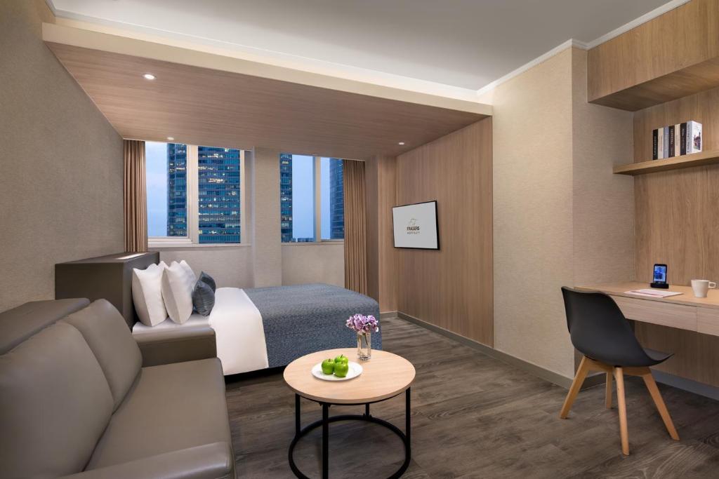 um quarto de hotel com uma cama, um sofá e uma mesa em Modena by Fraser Hong Kong em Hong Kong