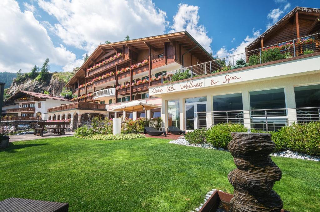 a building with a green yard in front of it at Sayonara Nature & Wellness Hotel in San Martino di Castrozza