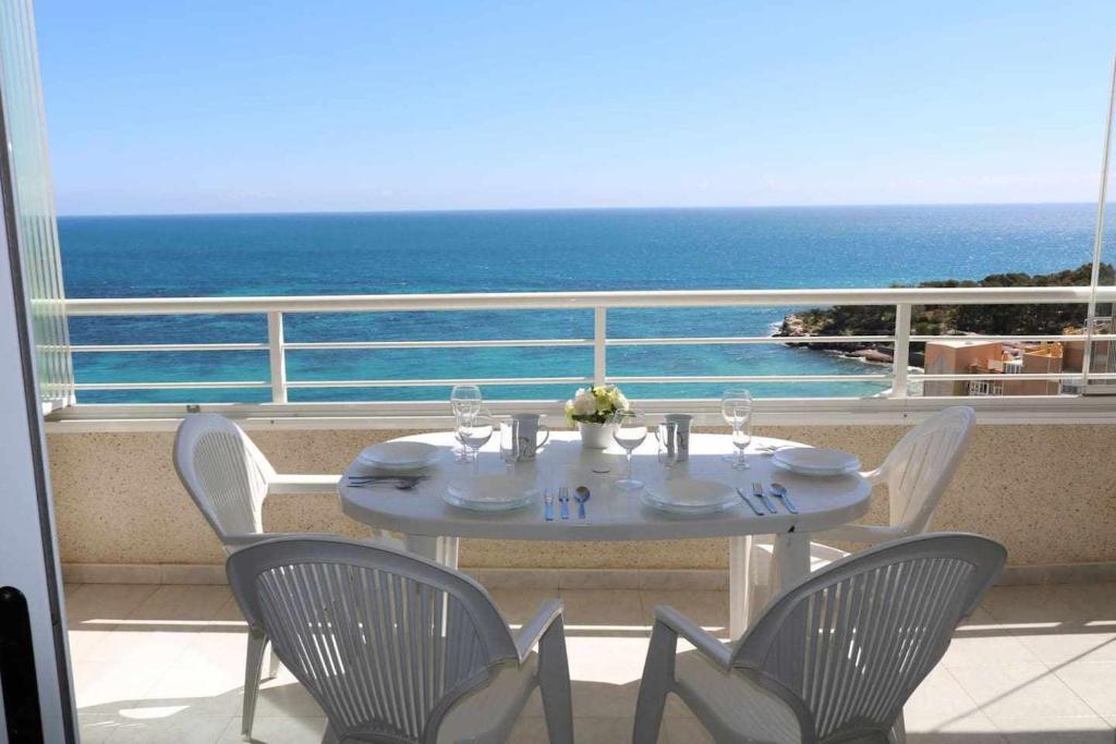 una mesa blanca y sillas en un balcón con vistas al océano en Apartamento Apolo16 2 dormitorios, en Calpe