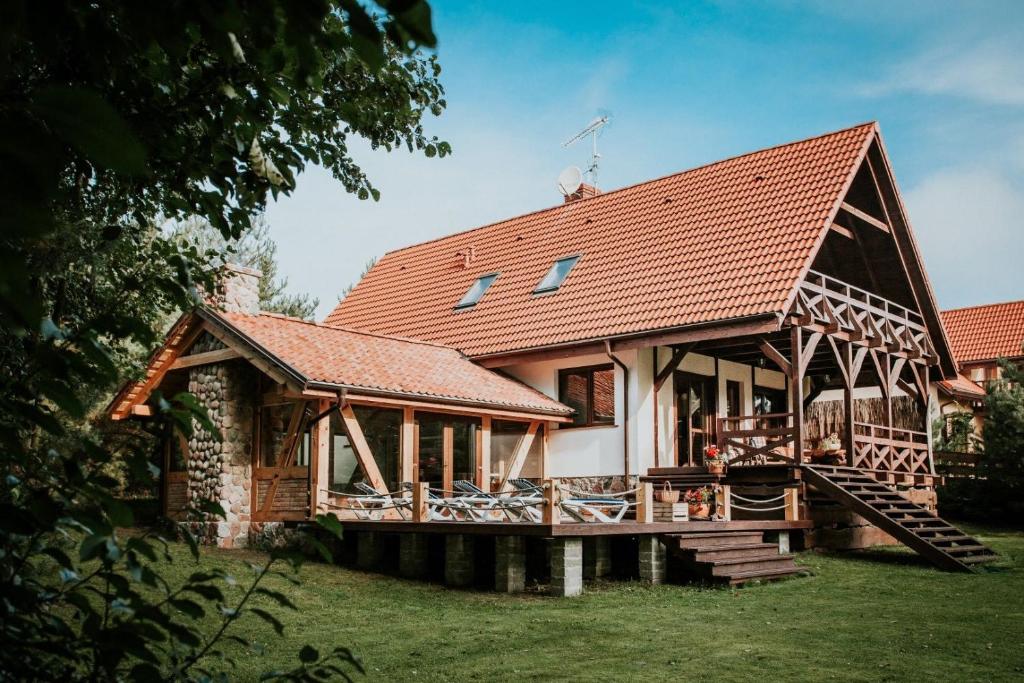 a large house with a wooden deck in the yard at Gustaw-Mazury - Całoroczny dom nad jeziorem Kalwa in Pasym