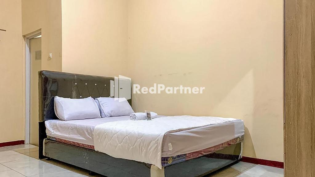 a bed with white sheets and pillows in a room at PSM Syariah Guest House RedPartner in Raab