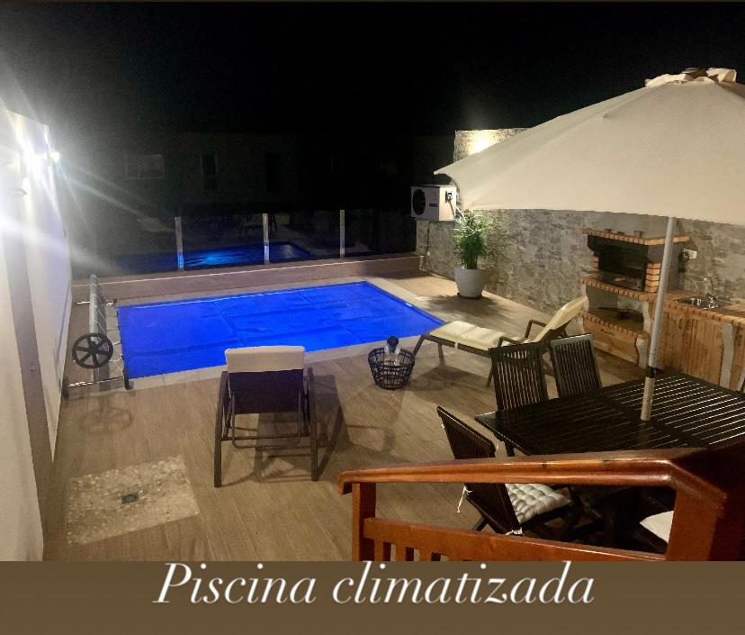 a swimming pool at night with chairs and an umbrella at Villa turmero in Puerto del Rosario