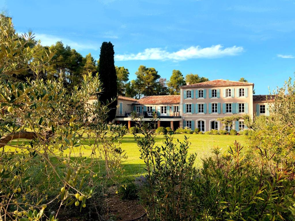een groot wit huis met een groene tuin bij Domaine de Valmouriane in Saint-Rémy-de-Provence