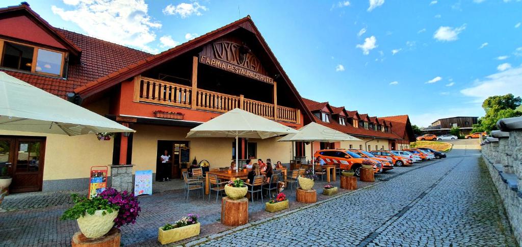 ein Gebäude mit Tischen, Stühlen und Autos, die auf einer Straße geparkt sind in der Unterkunft Hotel Farma Vysoká in Chrastava