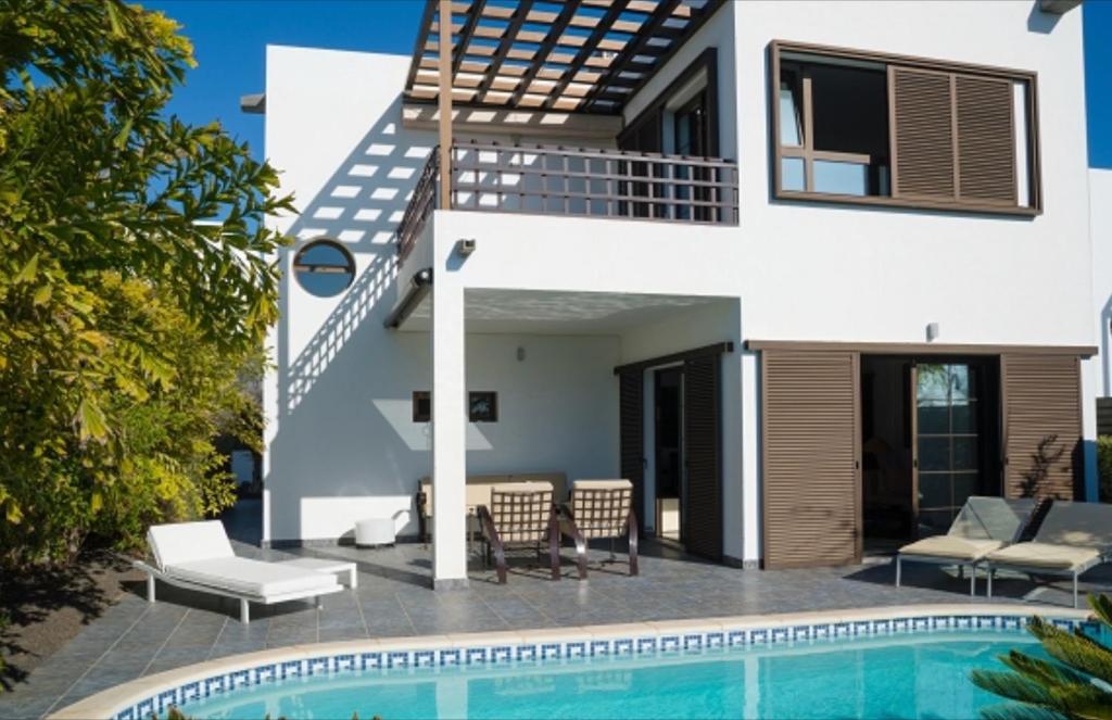a villa with a swimming pool and a house at Sea views modern villa for relaxing holidays in Costa Teguise