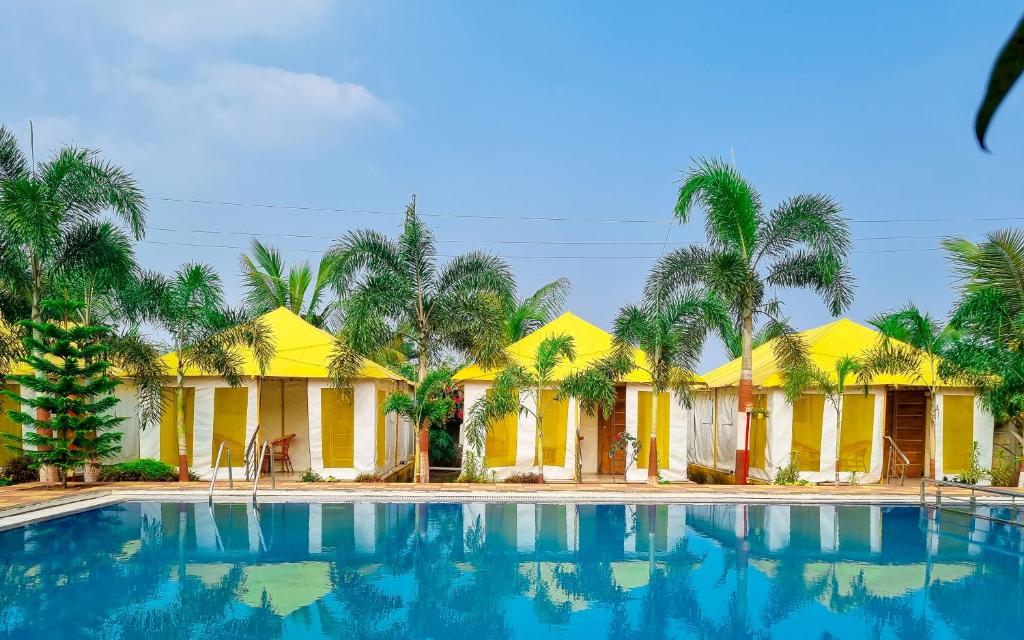 - une piscine en face d'une maison avec des palmiers dans l'établissement Natures Dreamland Holiday Homes, Igatpuri, à Igatpuri