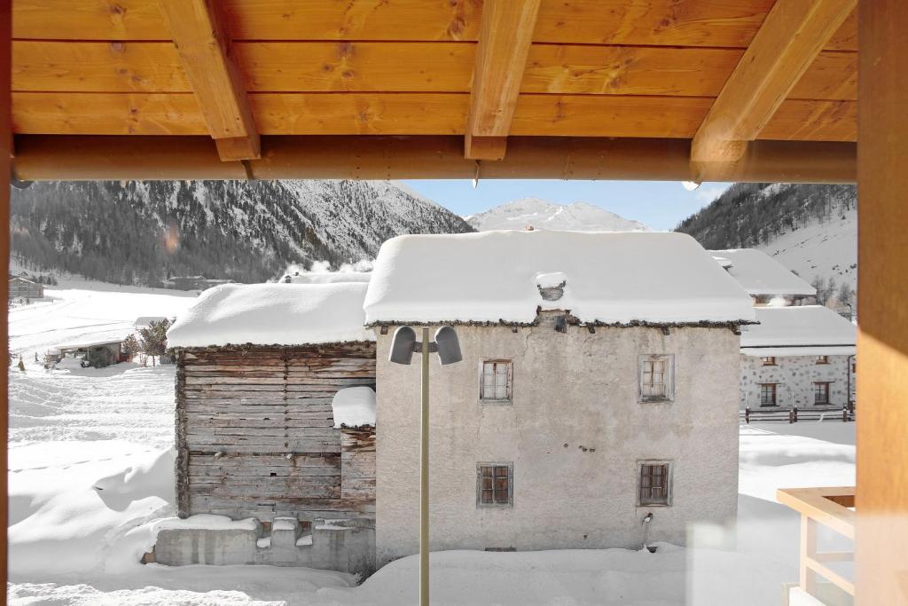 un bâtiment recouvert de neige avec un toit dans l'établissement Appartamento Cima Fopel, à Livigno