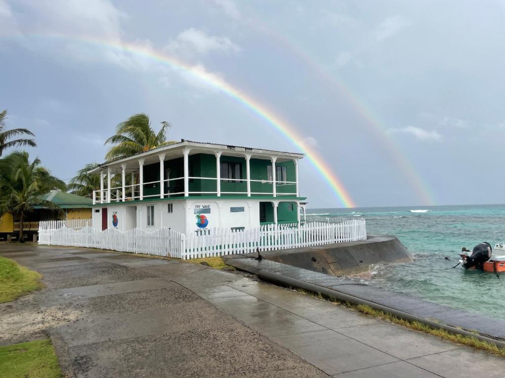 a rainbow over a house on a pier with water at The Wave Hostel Corn Island in Corn Island