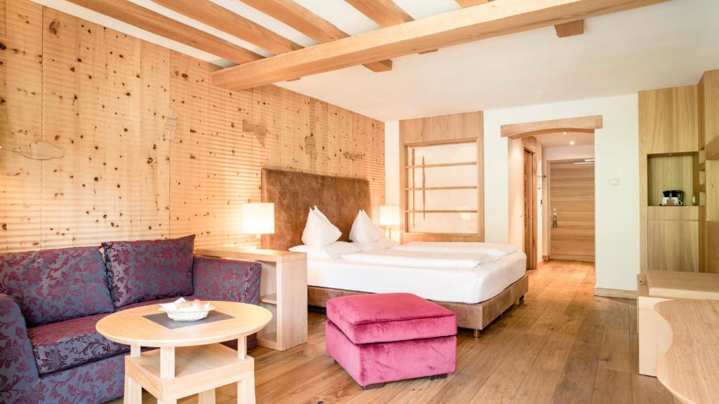 a bedroom with a bed and a couch and a table at Adler Spa Resort Dolomiti in Ortisei