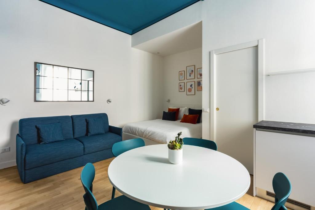 a living room with a white table and blue couch at Correggio Fiera Suite in Milan