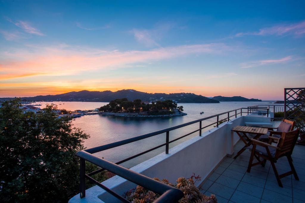 a balcony with a view of the water at sunset at Argo Pension in Skiathos